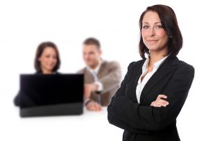 Frau im Business Outfit + Hintergrund Mann und Frau am Laptop Business Coaching